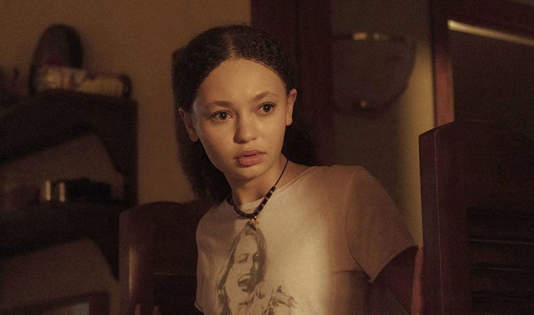 The character Sarah with her hair tied up, wearing a white blouse and looking to the side with a surprised expression.