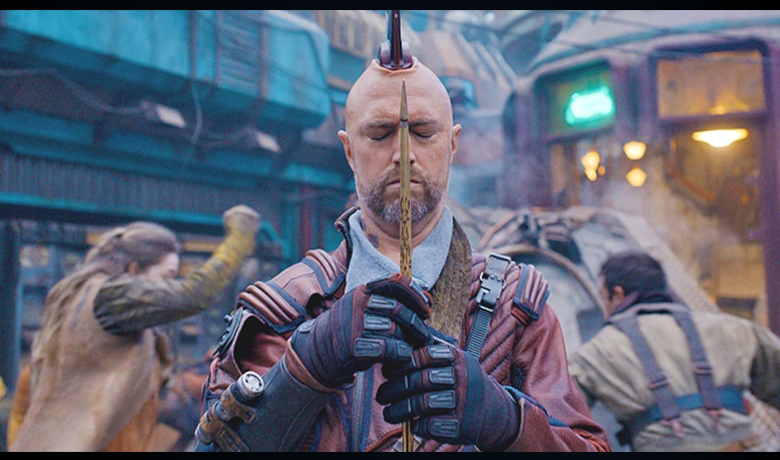 Kraglin segurando a arma que herdou de Yondu com uma expressão concentrada.