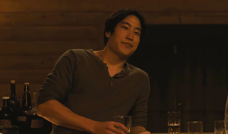 カウンターに寄りかかりながら、グラスに注がれた飲み物を持っているジェシーというキャラクターの画像